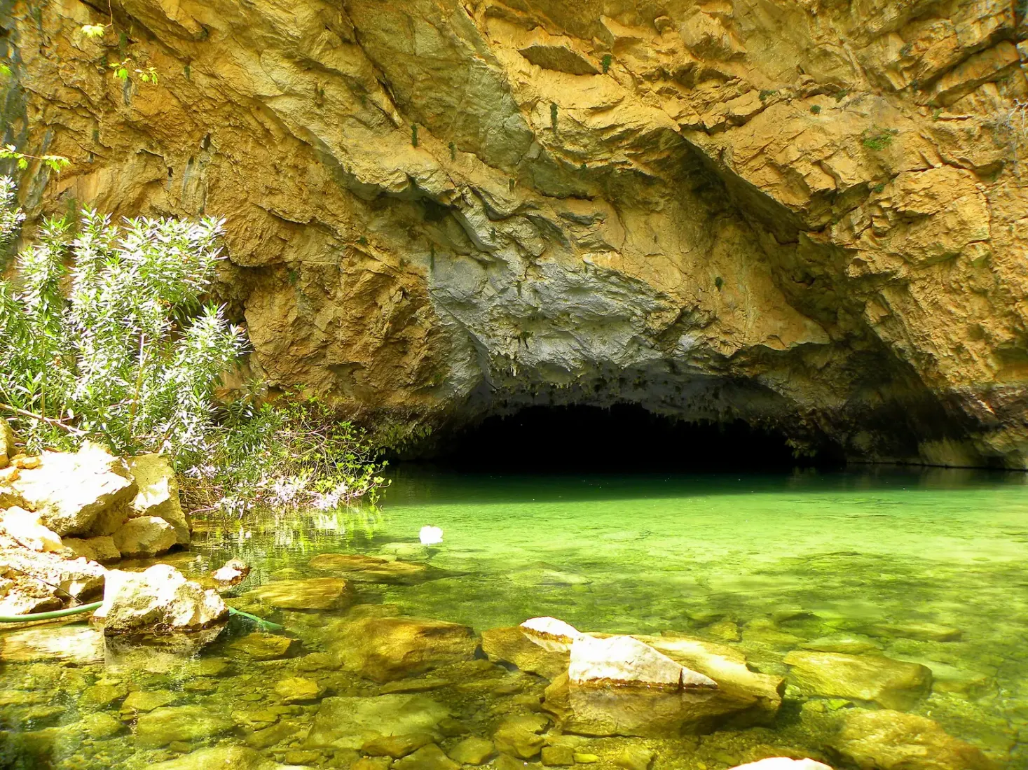Helder groen water onder de rotsen bij de ingang van de Altınbeşik grot