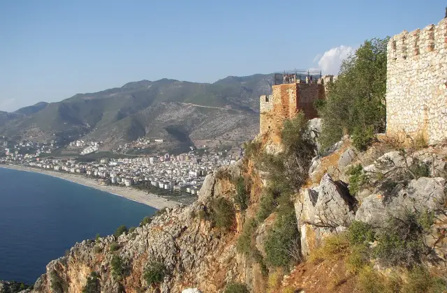 De muren van de binnenburcht van Alanya op de rotsrand met het Kleopatrastrand in de diepte