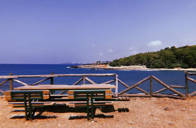 Picknicktafels boven de baai van het natuurpark İncekum met beboste kaap en blauwe zee
