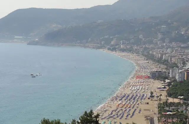 Het Kleopatrastrand van Alanya met rijen parasols langs de gebogen baai, gezien van bovenaf