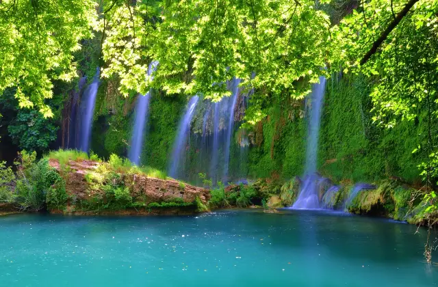 De Kurşunlu waterval die in een turquoise poel valt onder het groene bladerdak