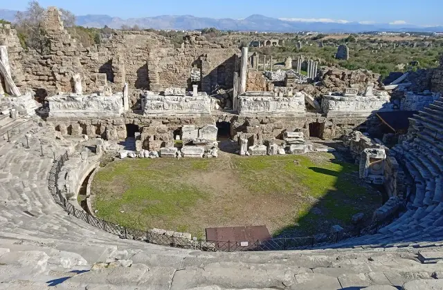 Het Romeinse theater van Side met de tribunes, het toneelgebouw en de bergen aan de horizon