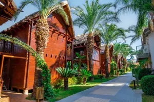 Bungalows van Long Beach Alanya in een tropische tuin met palmbomen.