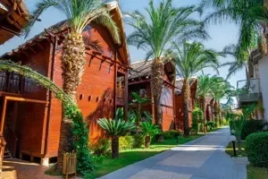 Bungalows van Long Beach Alanya in een tropische tuin met palmbomen.